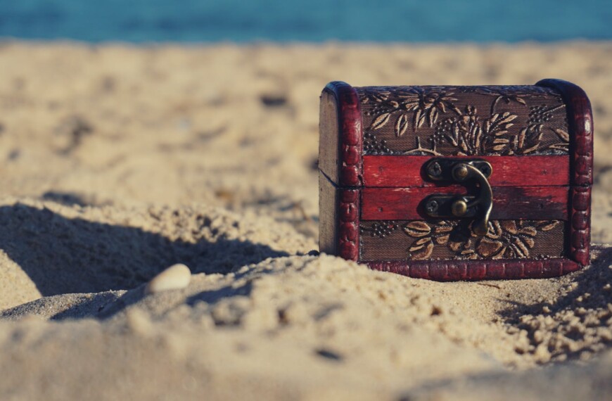 red and black wooden chest on white sand